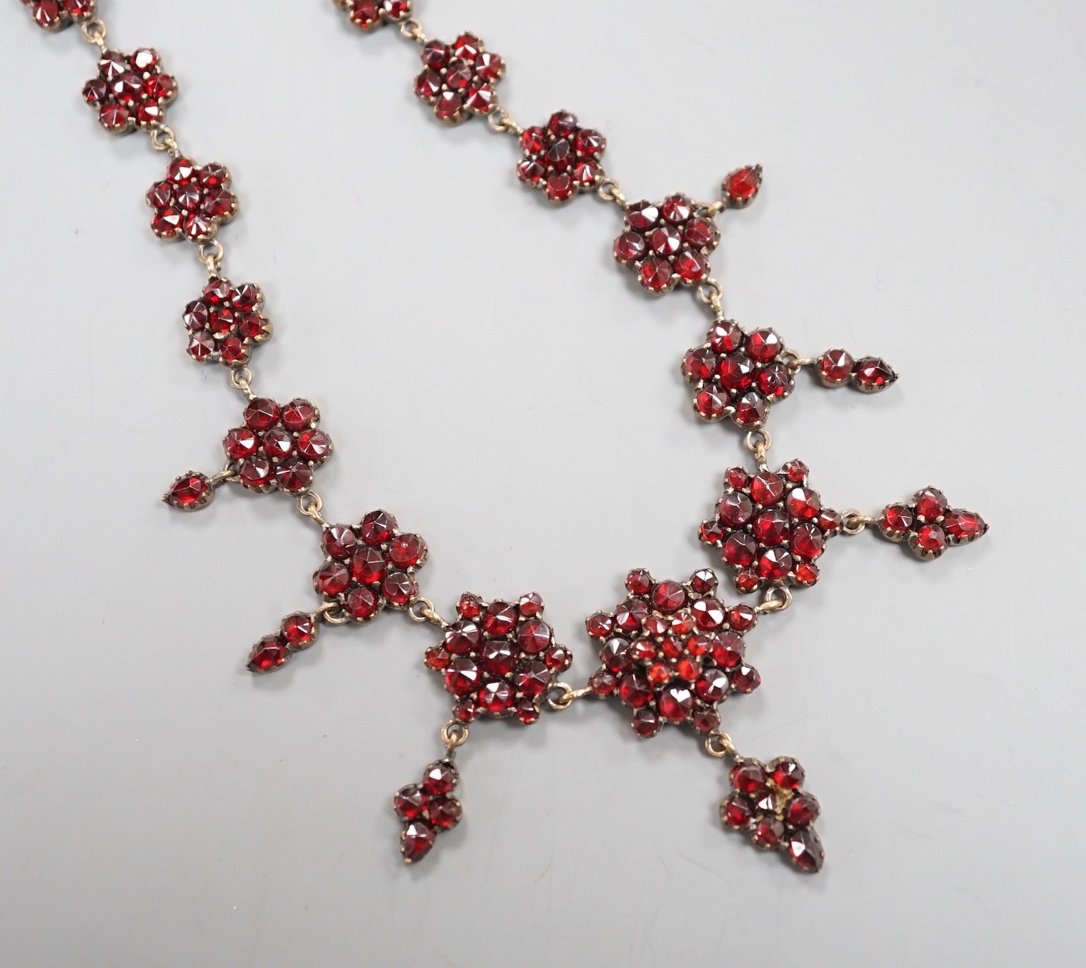 A late Victorian gilt and yellow metal, garnet cluster set drop necklace, 48cm.